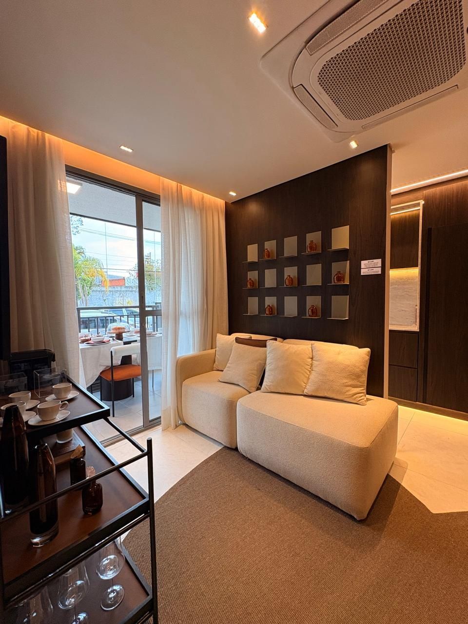 Sala de estar com acesso à varanda, sofá claro e cortina