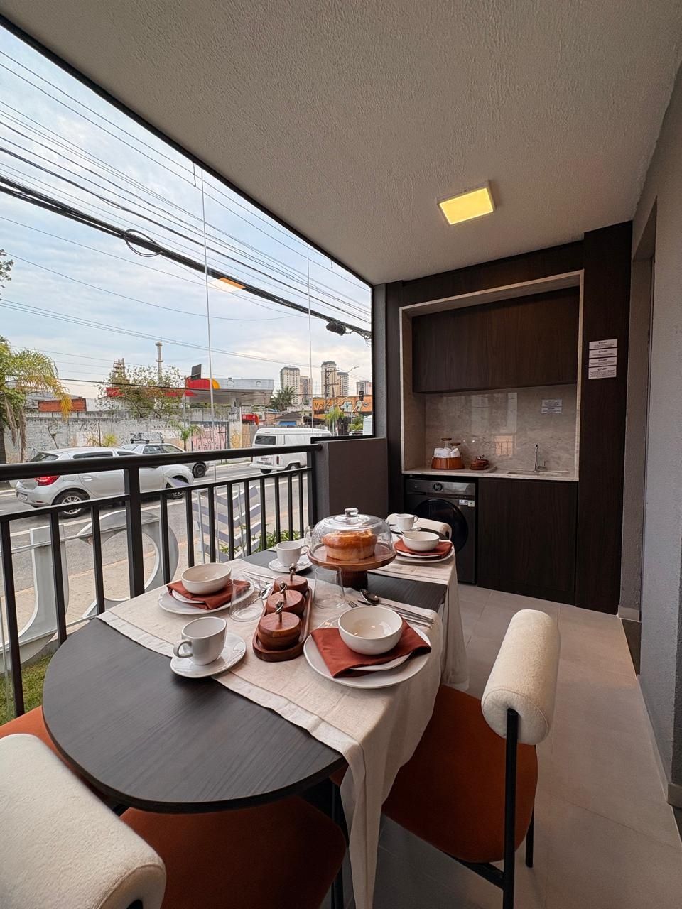 Varanda com mesa de jantar posta e vista para a rua