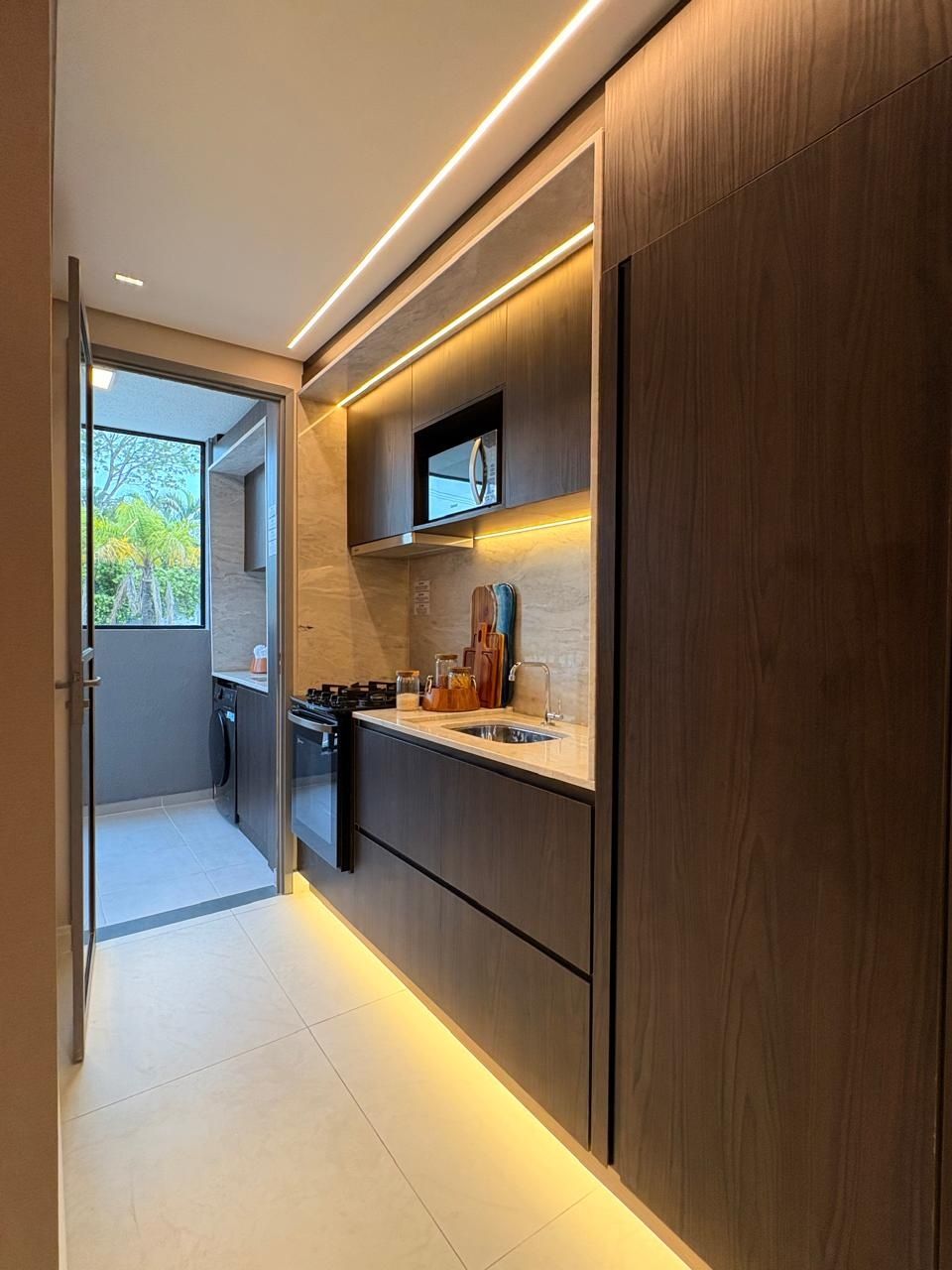 Cozinha linear com marcenaria escura e iluminação em LED